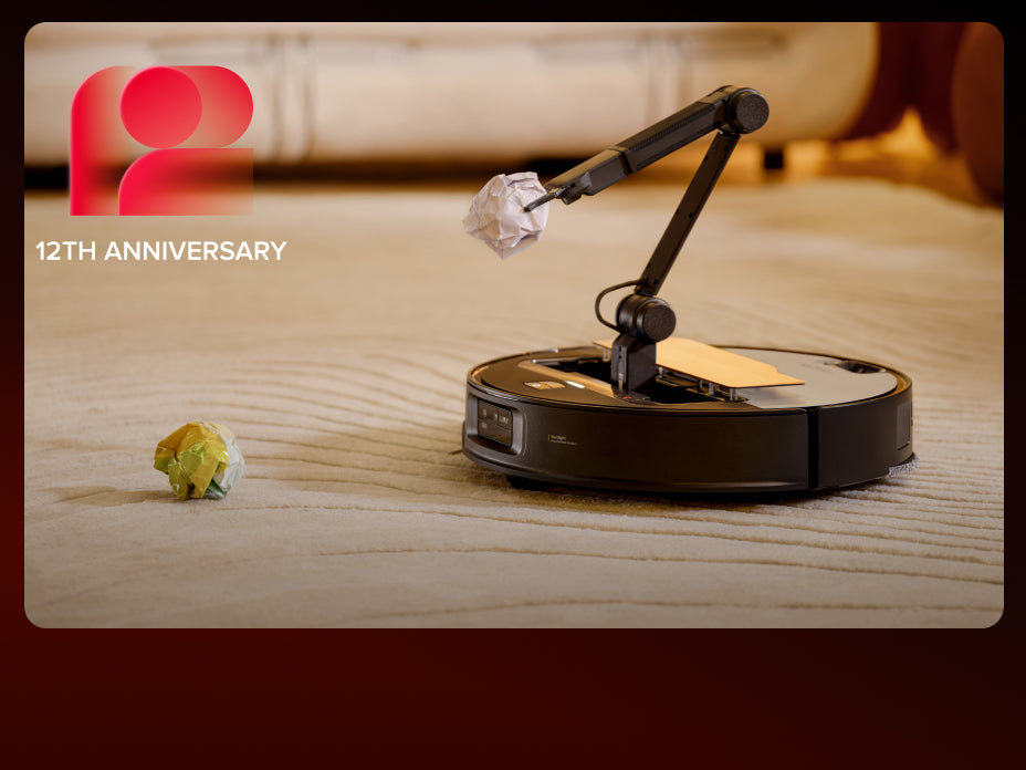 Black Roborock Saros Z70 robot vacuum on a rug, using an extended mechanical arm to lift a slipper